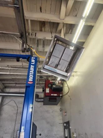 Unit heater hung over an automotive service bay, with a vehicle lift below