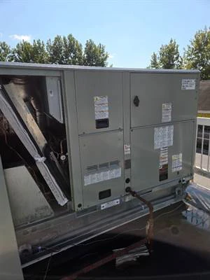 Packaged rooftop unit with its service panel open on a convenience store roof